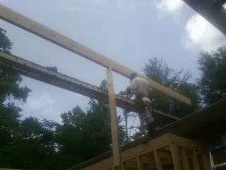 Carpenter setting a ridge beam over a new addition frame — Ice Dam Removal by Roofing Brothers in Lorain