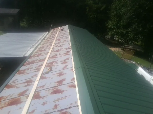 Old rusted panels beside newly installed green metal roofing — Wind Damage Roof Repair by Roofing Brothers in Lorain