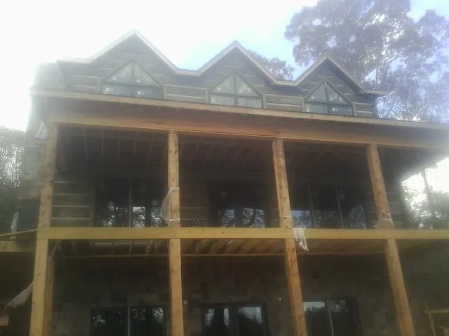 Dormers and porch framing on a large log home under construction — Roof Coating work by our crew in Lorain