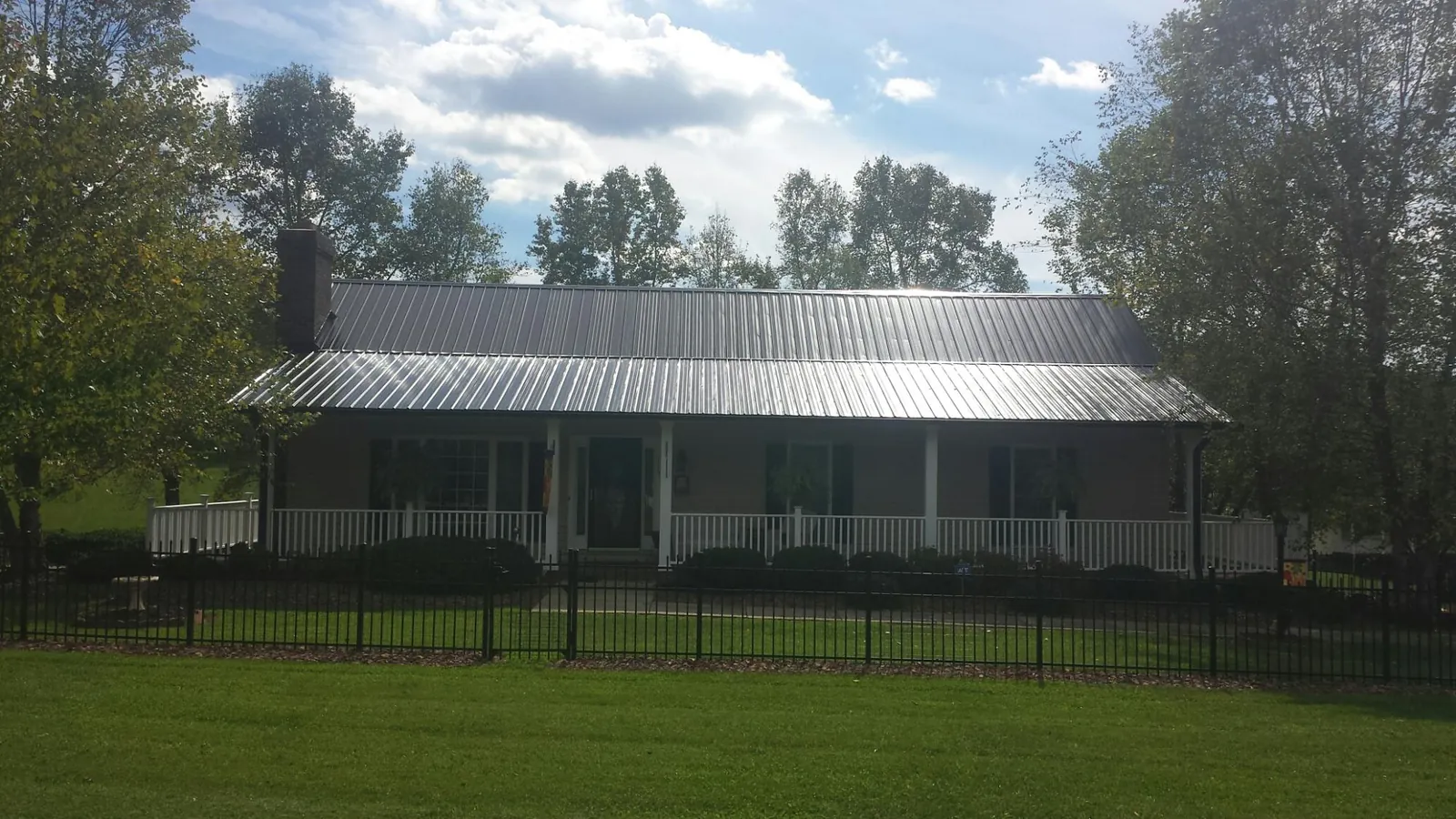 Gray metal roof on a brick ranch with a full width front porch — Gutter Guard Installation work by our crew in Lorain