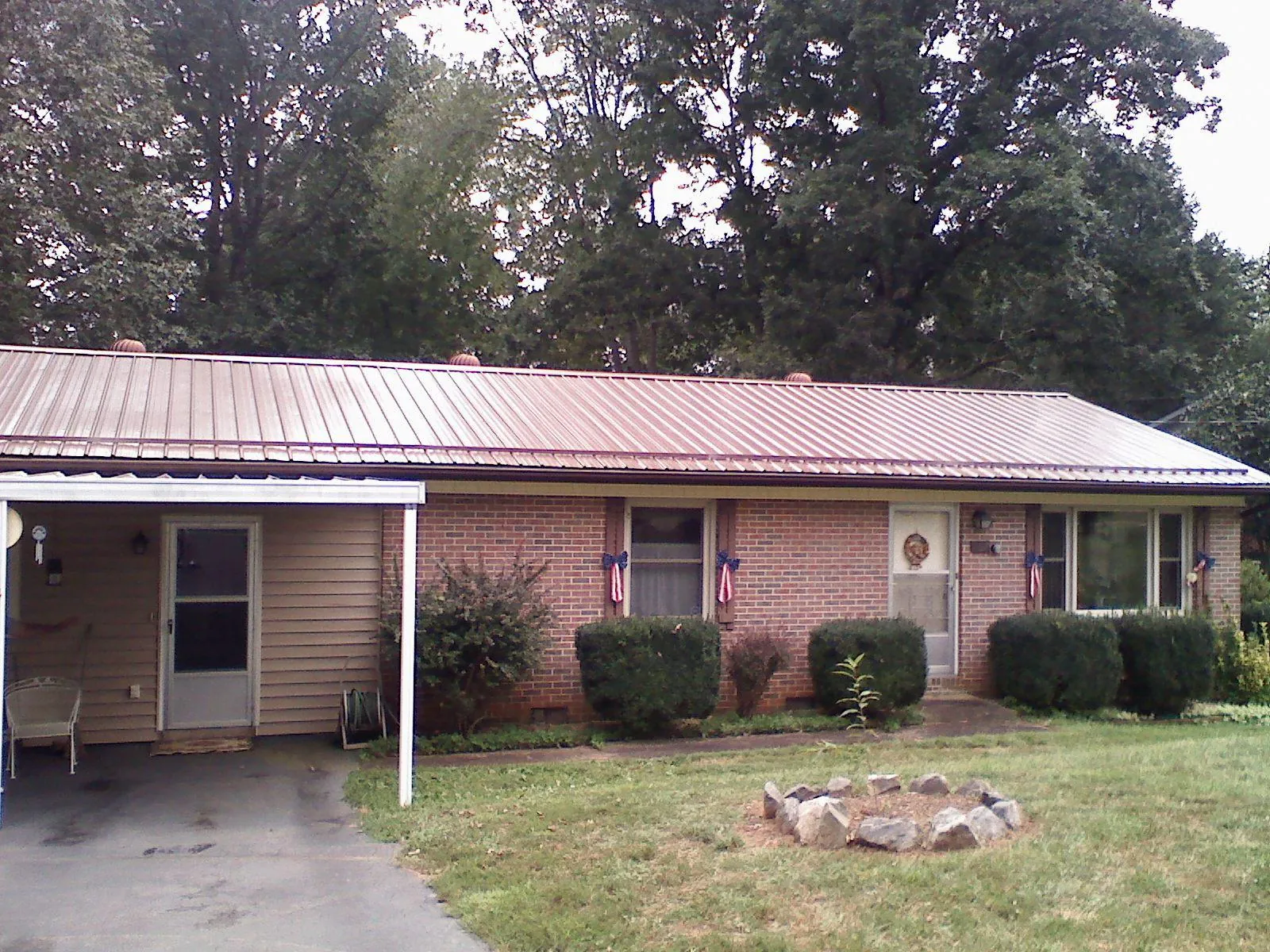 Bronze metal roof and carport on a brick ranch home — Roof Repair work by our crew in Lorain