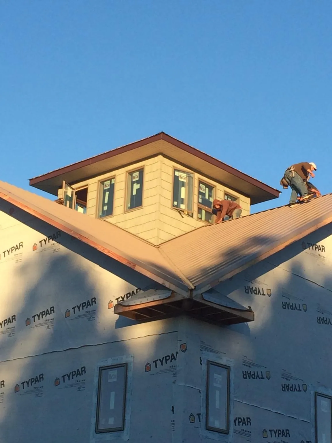 Roofers working around a rooftop cupola on a new metal roof at sunset — Roof Waterproofing in Lorain by Roofing Brothers